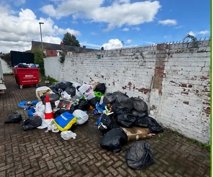 Bin bags and dumped household rubbish piled in a cobbled back street