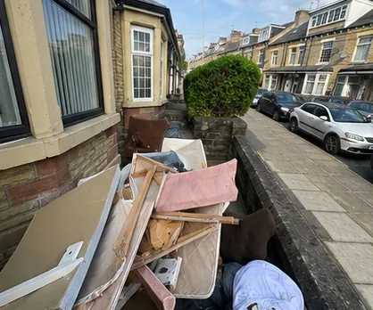 Front garden of a terraced house filled with dumped furniture and building waste